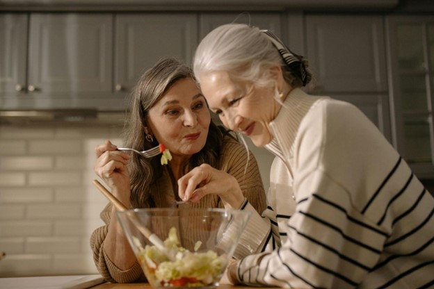 Elderly woman and younger caregiver sharing a warm moment in the kitchen during the holidays